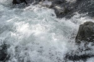Détail d’un torrent de montagne : écume et tourbillons d’eau entre les rochers 